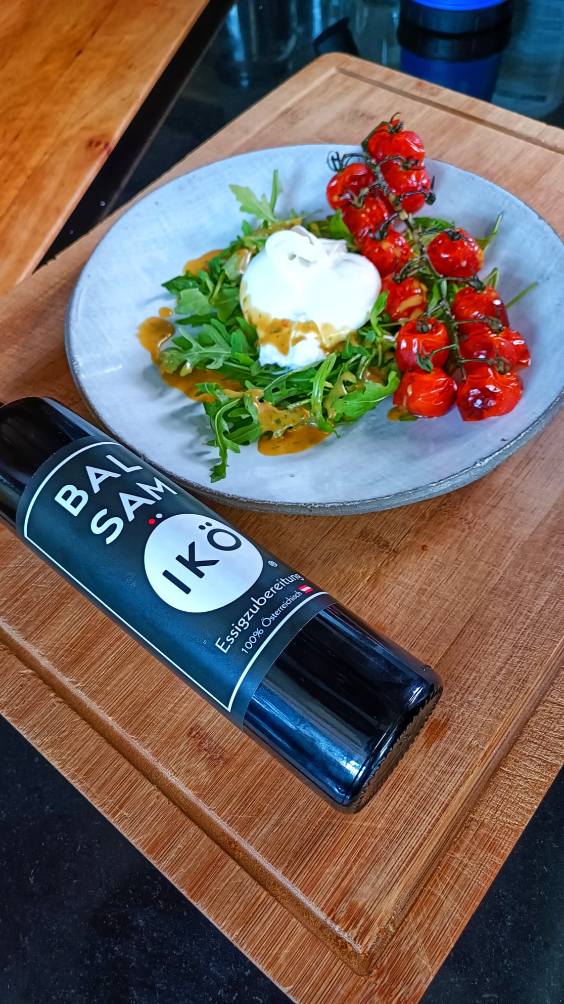 Flasche BALSAMIKÖ an einem Teller mit Ruccola, Tomaten Salat