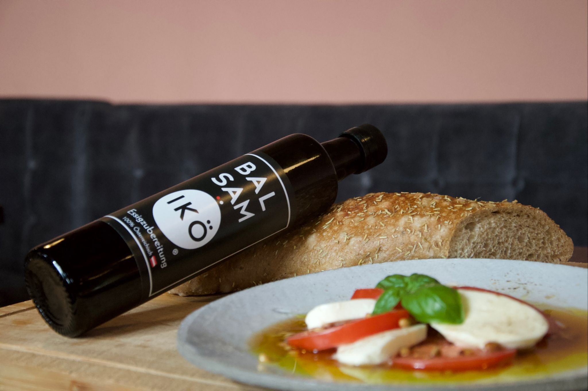 BALSAMIKÖ Flasche, platziert an einem Teller Mozzarella auf Tomaten Caprese mit Basilikum dekoriert, an einem Stück Weißbrot.